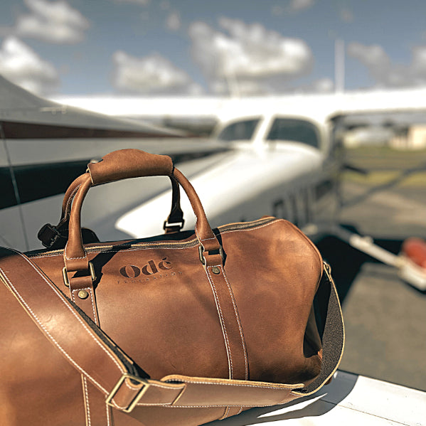 leather weekender bag sitting on a small plane wing in the sun